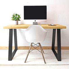 a desk with a computer on it in front of a white wall and wooden floor