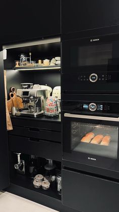 a kitchen with black cabinets and an oven filled with food on top of counter tops