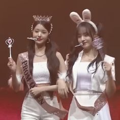 two young women dressed in bunny ears and white outfits, one holding a key to her mouth