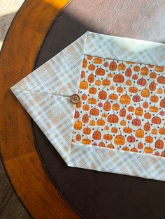 an orange and white quilted table runner with pumpkins on it, sitting on a wooden table