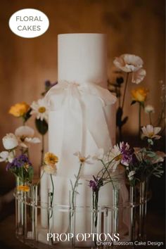 a white wedding cake with flowers in vases on the side and an ad for floral cakes