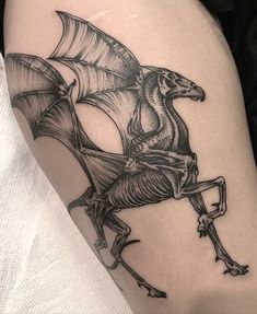 a black and white image of a dragon on the thigh