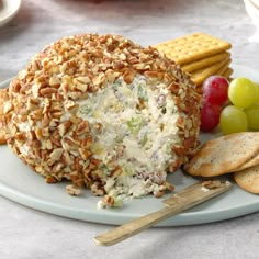 a cheese ball on a plate with crackers and grapes