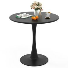 a black table with an orange and some flowers on it, sitting in front of a white background