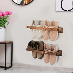 several pairs of shoes are hanging on a wall with a mirror and vase in the background