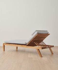 a wooden chaise lounger with grey cushions on it's back and legs