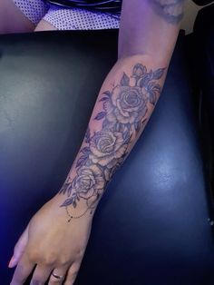 a woman's arm with flowers on it and her hand holding the wrist tattoo