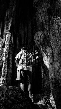 black and white photograph of a man walking through a cave