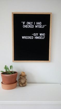 a blackboard mounted on the wall above a potted plant