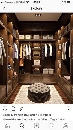 a large walk in closet with lots of clothes on the shelves and an ottoman underneath