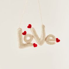 the word love is made from felt and red pom - poms on a white background