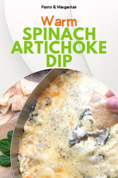 a person dipping tortilla chips into a pan with spinach artichoke dip