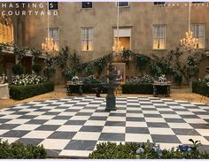 a large checkered floor in front of a building with chandeliers hanging from the ceiling