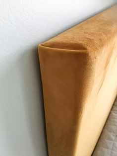 a close up of a bed with a wooden headboard and white walls in the background