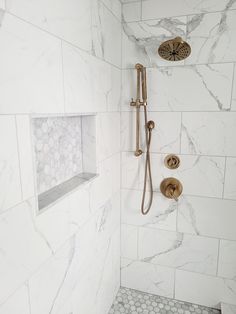 a bathroom with marble walls and floor, shower head, and hand held shower faucet