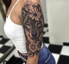 a woman's arm with a wolf and flowers tattoo on the left side of her body