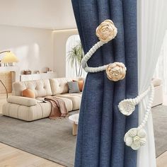 a living room with blue curtains and white flowers on the curtain rod, in front of a beige couch