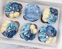 cupcakes decorated with blue and white frosting in a box