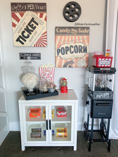 a small bar cart is in front of a wall with movie posters and popcorn on it