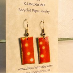 a pair of earrings with red and yellow designs on them sitting on a piece of paper