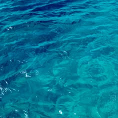 the water is very clear and blue with little bubbles on it's surface as seen from a boat