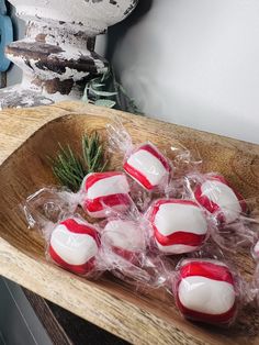 red and white candies in plastic wrap on a wooden platter with pine branches