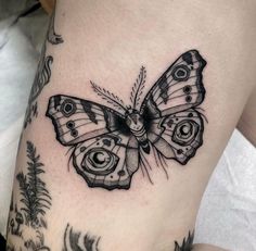 a black and white butterfly tattoo on the thigh