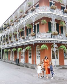 three women and two children standing in front of a building with flowers on the balconies