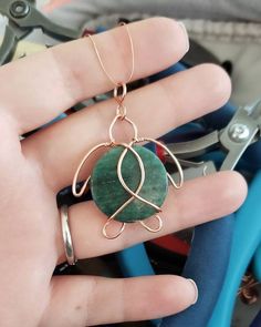 a hand holding a wire wrapped ring with a green stone on it's side