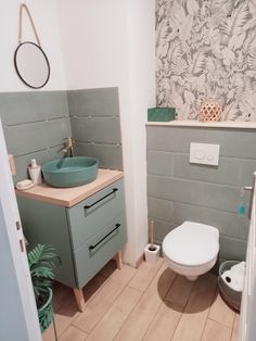 a bathroom with a toilet, sink and green plant in the corner on the wall