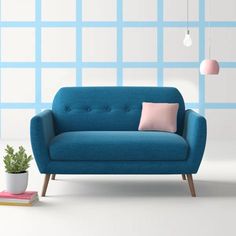 a blue couch sitting next to a potted plant on top of a white floor