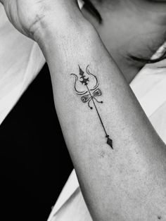 a woman's arm with an arrow tattoo on it