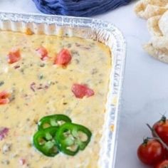 a casserole dish with tomatoes and green peppers in it next to some chips