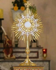 a golden cross on top of a wooden stand in front of a table with candles