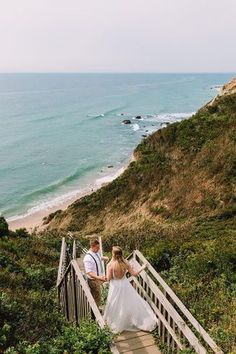 a bride and groom walking up stairs to the beach