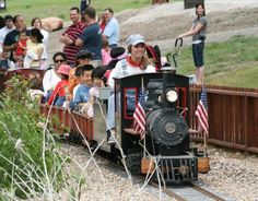 people are riding on a miniature train with an american flag painted on the front and side