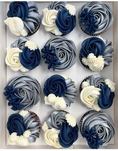 twelve cupcakes with blue and white frosting in a box