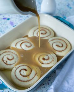 some food is in a white dish on a blue and white tablecloth with a spoon