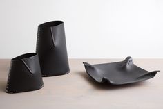 two black vases sitting on top of a wooden table