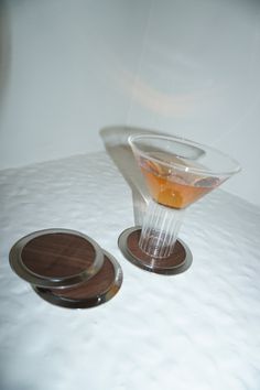 a drink glass with an orange in it sitting on a table next to two coasters