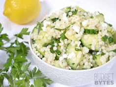 a white bowl filled with cucumbers and feta cheese next to a lemon