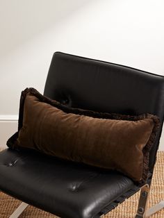 a black chair with two brown pillows on it