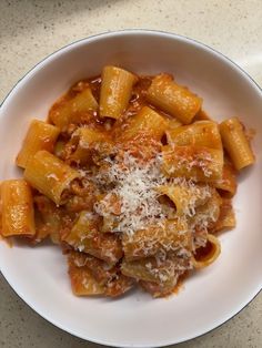 a white bowl filled with pasta covered in sauce and parmesan cheese on top