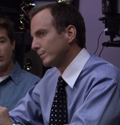 two men sitting next to each other in front of a computer screen and holding their hands together