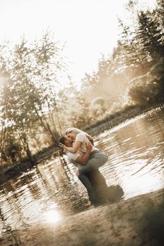 a man holding a woman in his arms while standing in the middle of a body of water