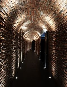 the tunnel is made out of bricks and has lights on each side to illuminate light