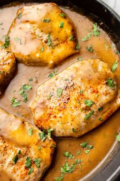 three pieces of chicken covered in gravy and garnished with parsley