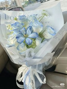 a bouquet of blue and white flowers sitting in the back seat of a car