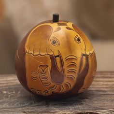 an elephant painted on top of a pumpkin sitting on a wooden table next to a wall