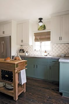 a kitchen with wooden floors and white cabinets, an island in the middle is surrounded by dishes